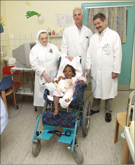 Stationsleitung Schwester Donatilla Seidenschwarz, Kinderchirurg Dr. Andreas Schmidt und Chefarzt Dr. Michael Heinrich mit Roselia, die ihr Bein nach der ersten Operation schon fast ausstrecken kann. © KJF/Karg